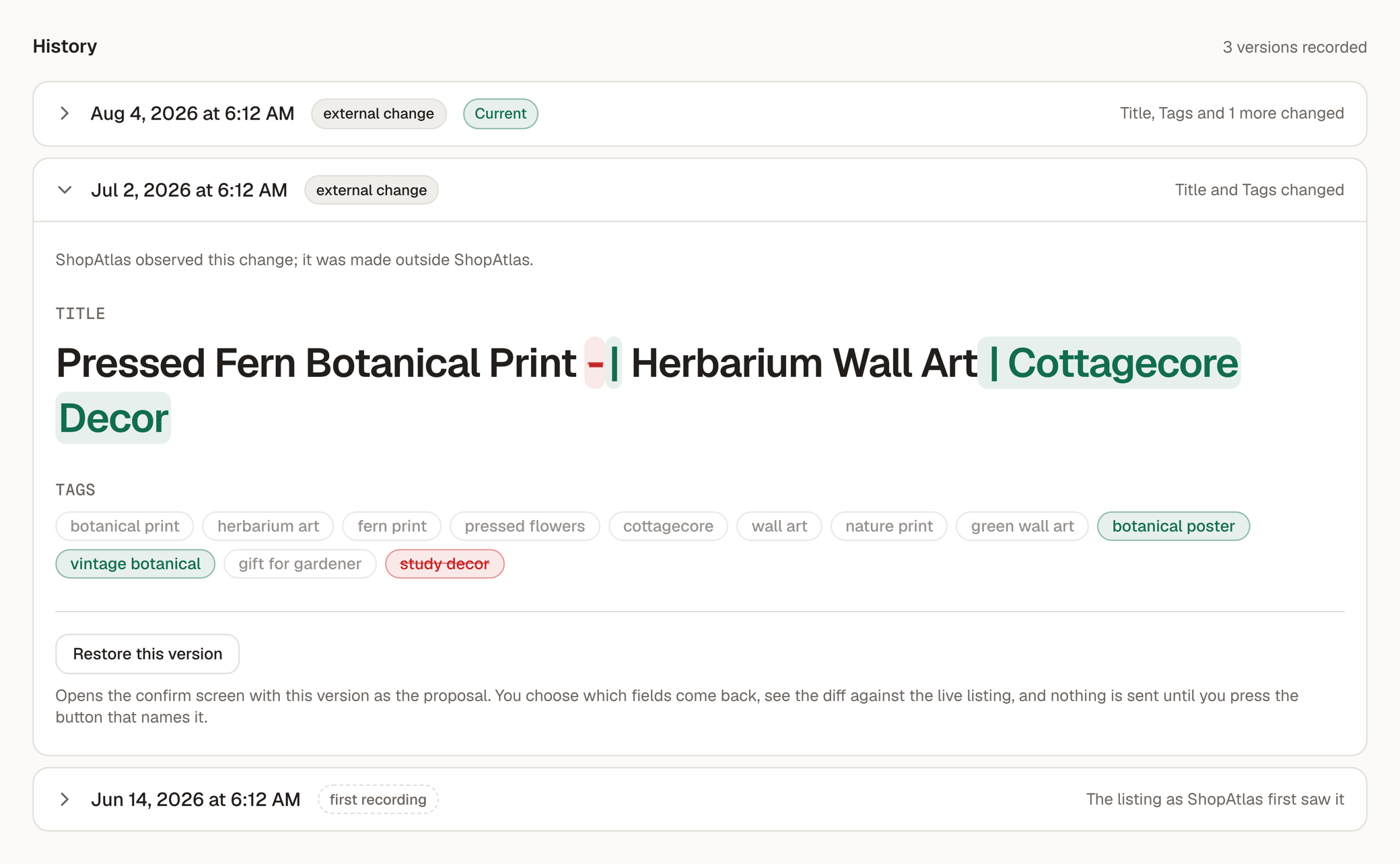 A listing's version history in ShopAtlas: three recorded versions, newest first, each
                   badged with where the change came from. The middle one is expanded to show the exact
                   difference — the words added to the title highlighted against the words removed, and
                   the tags added and struck through — above a Restore this version link.